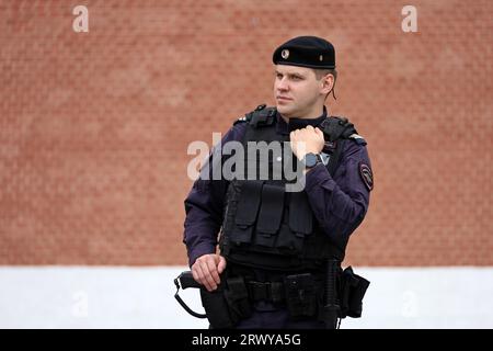 Russian police officer of special forces in bulletproof vest standing on city street on Kremlin background Stock Photo