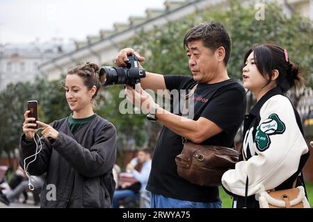 Asian tourists photograph on camera standing on street in Moscow Stock Photo