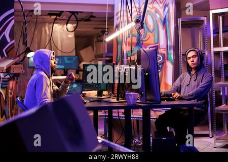 Hackers using spyware to gain access to confidential information from database server. Criminals breaking into computer network system and working together in abandoned warehouse Stock Photo