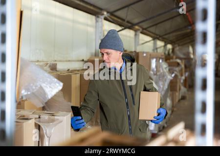 Warehouse worker using his smartphone to take photographs Stock Photo