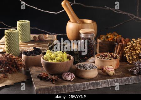 Many different dry herbs, flowers and mortar with pestle on dark grey table Stock Photo