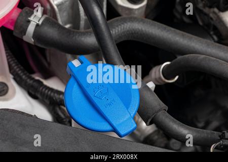 Windshield washer fluid reservoir under the hood of vehicle. Automotive service, repair and maintenance concept. Stock Photo