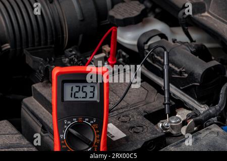 Battery tester checking car battery voltage. Vehicle maintenance, repair and service concept. Stock Photo
