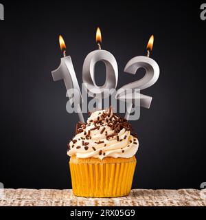 birthday cupcake with number 102 candle - Celebration on dark background Stock Photo