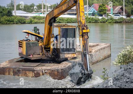 A floating dredger is dredging the bottom of the pond, Thailand Stock Photo