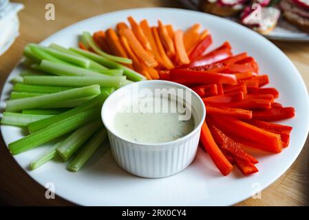 sliced vegetable sticks on a white plate with dipping sauce close up Stock Photo