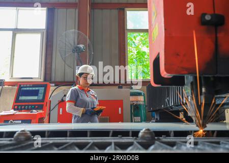 Luannan County, China - August 10, 2023: Workers are operating CNC machine tools for cutting operations in a factory. Stock Photo