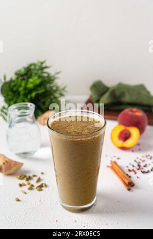Smoothie with peach, ginger and spices in glass on white background Stock Photo