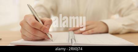 Business woman takes notes in organizer at table in office. Stock Photo