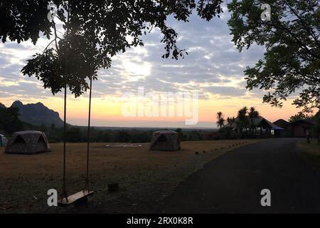 A photo taken in the morning before sunrise inside Phu Pha Man National Park, Thailand. Tourist tents are visible in a wide field inside the park. In Stock Photo