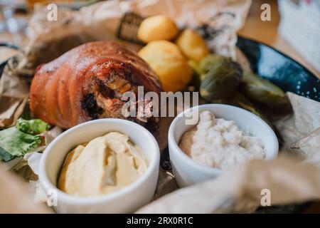 Baked pork shank served with baked potatoes, horseradish, mustard and pickled cucumbers. Traditional Polish dish Stock Photo