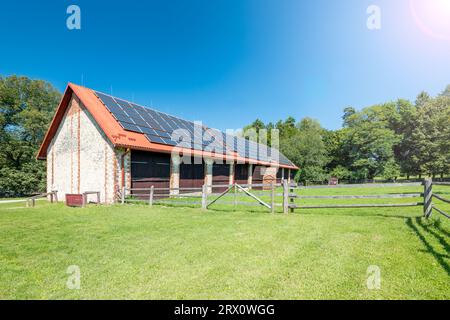 Big brick barn on a farm. Solar panels installed on the roof of the barn. Stock Photo