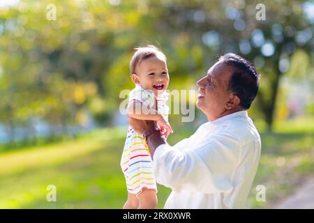 Father and son in sunny park. Loving family playing outdoor. Grandfather holding little boy high in the air. Senior man and adorable baby play Stock Photo
