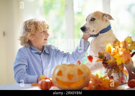 Family carving pumpkin for Halloween celebration. Boy and girl child cutting jack o lantern for traditional trick or treat decoration. Stock Photo