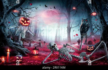Halloween - Skeletons In Spooky Forest At Moonlight - Jack O’ Lanterns In Cemetery At Twilight Stock Photo