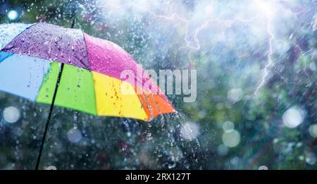 Rain On Rainbow Umbrella - Weather Concept - Spring And Fall Shower With Abstract Defocused Drops And Light Flare Effects Stock Photo