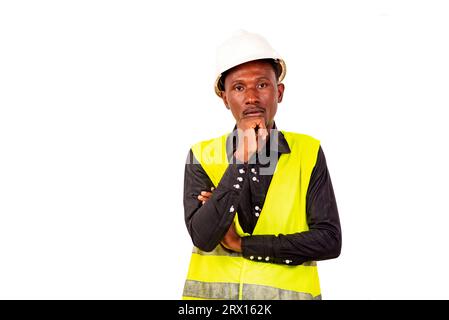 young man engineer wearing green vest and white safety helmet is thinking with crossed arm and raised hand on chin. Stock Photo