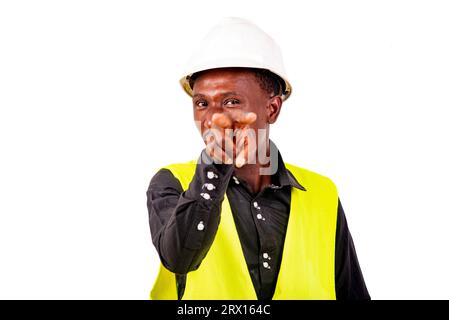 Young man engineer wearing green vest and white safety helmet while making the gesture of looking at you with two fingers. Stock Photo