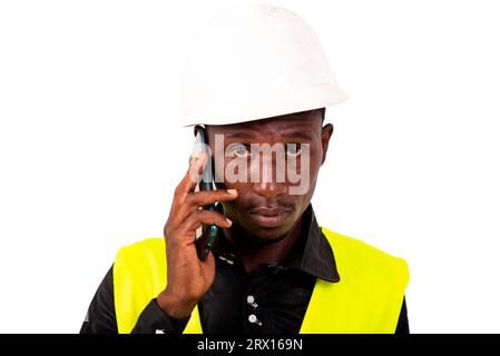 young man engineer wearing green vest and safety helmet while talking on mobile phone. Stock Photo