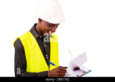 young man inspector architect wearing green vest and safety helmet writing in clipboard. Stock Photo