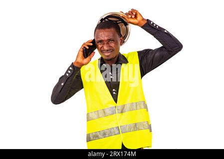 young man engineer wearing green vest and safety helmet while talking on mobile phone. Stock Photo