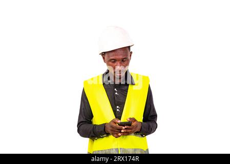 young man engineer wearing green vest and safety helmet using mobile phone. Stock Photo