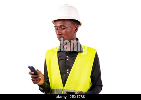 young man engineer wearing green vest and safety helmet while holding two mobile phones. Stock Photo