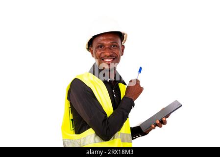 a construction engineer with hard hat standing over white background holding a tablet and pen looking at the camera laughing. Stock Photo