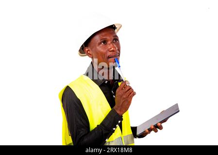 a construction engineer with safety helmet standing on white background thinking while holding a tablet. Stock Photo