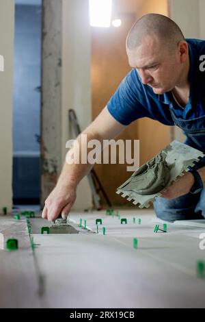 Tiler placing ceramic wall tile in position over adhesive with lash tile leveling system. Ceramic Tiles Stock Photo