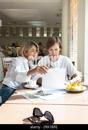 two cute, beautiful women signing papers in a hotel restaurant Stock Photo