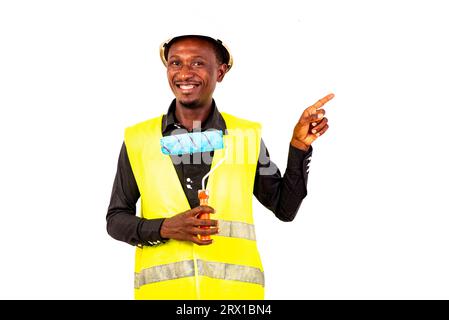 young painter man wearing green vest and holding brush roll and pointing index finger aside smiling. Stock Photo