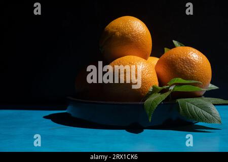 Bowl of oranges on a blue table. Stock Photo