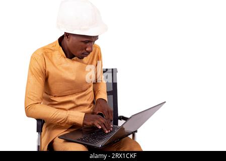 young business man engineer wearing white hard hat sitting on chair and working with laptop. Stock Photo