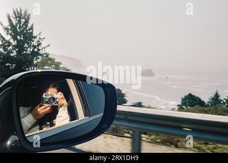 Woman taking a mirror selfie with a vintage film camera on the p Stock Photo