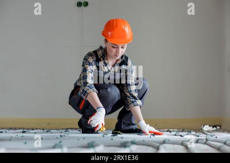 Woman worker is installing underfloor heating system. Warm floor heating system Stock Photo