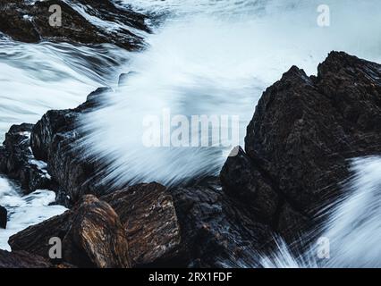 ocean waves break on rocks along maine coast Stock Photo