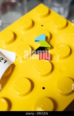 Photograph of 4 LEGO bricks in blue, green, black and red, on top of a giant yellow LEGO brick lunch box, in the Mini Chef restaurant in the LEGO Hous Stock Photo