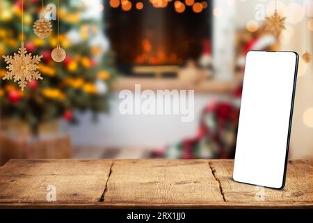 Smartphone with white blank screen on Christmas background with fireplace.  Stock Photo