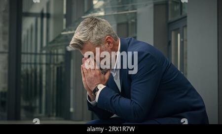 Pensive Caucasian middle-aged old man feeling headache eyes strain discomfort thinking thoughtful unwell senior businessman worried problem migraine Stock Photo