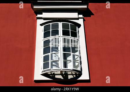 old style wood bow window in stucco exterior wall in closeup view. arched shape. outer operable wings on hinges. strong light. European architecture Stock Photo