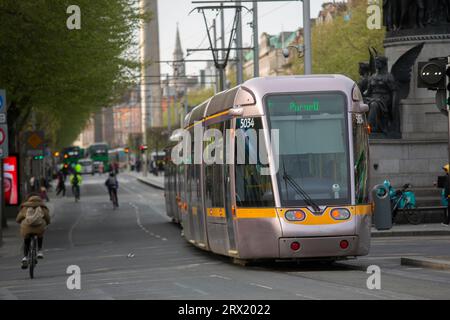 A Luas tram in O'Connell Street with cyclists visible too. Dublin, Ireland Stock Photo