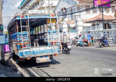 Phuket, Thailand - 26 February 2018: Street with bus, motorcyclists and local people Stock Photo