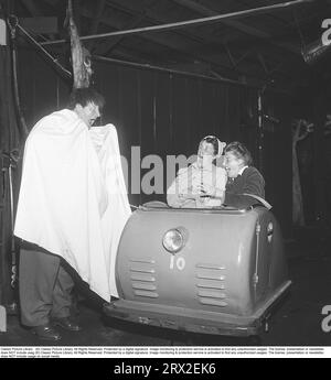 Amusement park in the 1950s. Two women are riding the scary ride and passes a man dressed as a ghost wearing a white sheet. The look surprised and afraid and are holding their hands in horror. Sweden 1952 Kristoffersson ref BD25-2 Stock Photo