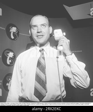 In the 1950s. At an exhibition, a seller of electrical products demonstrates the American vibrator from the company Pifco. With its design in bakelite and its vibrating function, the device was a novelty for many fair visitors. It seems to work for use on the whole body and he holds it close to his cheek to show how it works.  The photo was taken at a consumer fair where the product was presented to the public for the first time.   Sweden 1951. Kristoffersson ref BD39-7 Stock Photo