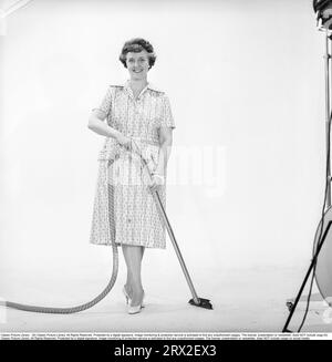 Cleaning day in the 1960s. A woman is standing holding a vacuum cleaner, looking happy. Sweden 1960. Kristoffersson ref CN109-3 Stock Photo