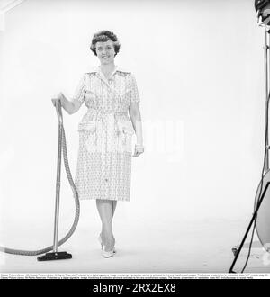 Cleaning day in the 1960s. A woman is standing holding a vacuum cleaner, looking happy. Sweden 1960. Kristoffersson ref CN109-2 Stock Photo