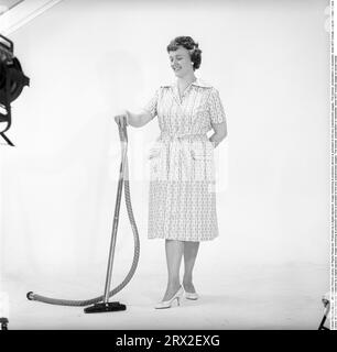 Cleaning day in the 1960s. A woman is standing holding a vacuum cleaner, looking happy. Sweden 1960. Kristoffersson ref CN109-11 Stock Photo