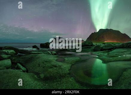 Green lights of Aurora Borealis (Northern Lights) glowing over mountains and Uttakleiv beach, Vestvagoy, Lofoten Islands, Nordland, Norway Stock Photo