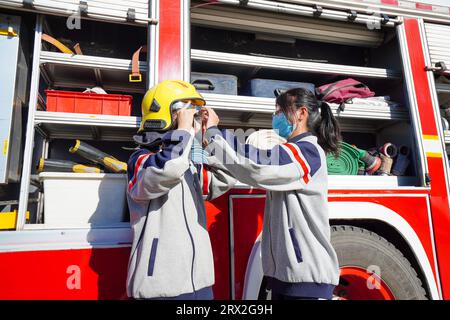Luannan County, China - September 23, 2022: Two female students are experiencing wearing fire-fighting clothing, North China Stock Photo